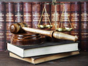 Wood gavel, soundblock, scales and stack of old books against the background of a row of antique books bound in leather